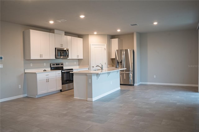 kitchen featuring stainless steel appliances, light countertops, a sink, a center island with sink, and baseboards