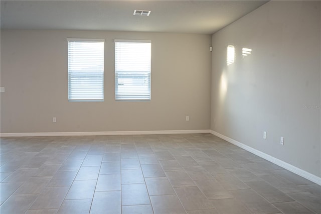 spare room featuring baseboards, visible vents, and light tile patterned flooring