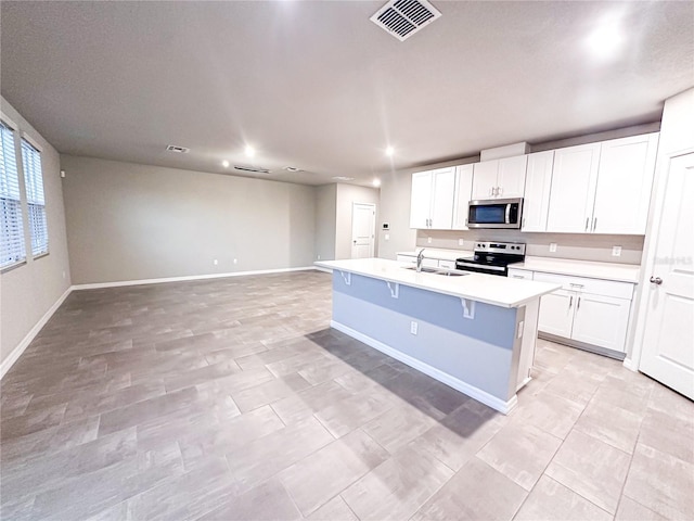 kitchen with a sink, a center island with sink, visible vents, light countertops, and appliances with stainless steel finishes
