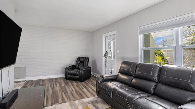 living room with wood-type flooring and brick wall