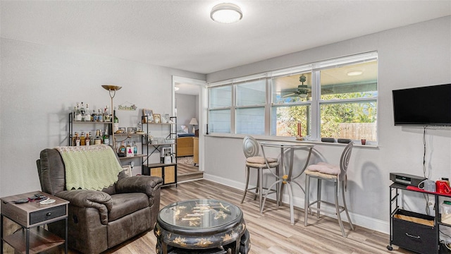 sitting room with ceiling fan, hardwood / wood-style floors, and bar area