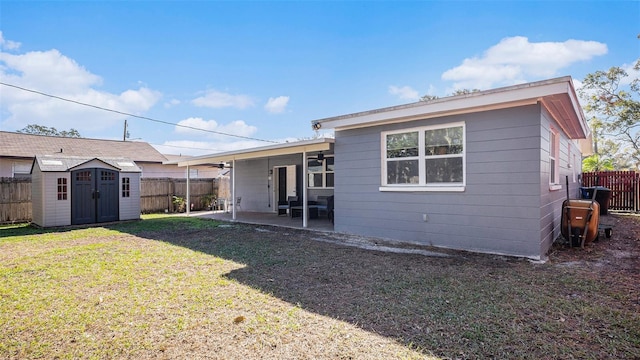 back of house with a lawn, a patio, and a storage shed