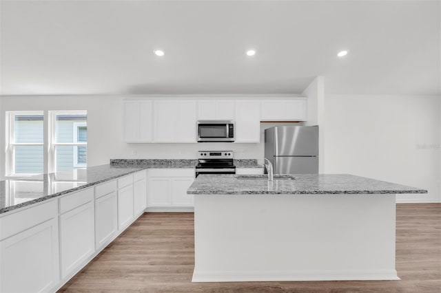 kitchen with sink, light hardwood / wood-style flooring, light stone countertops, white cabinetry, and stainless steel appliances