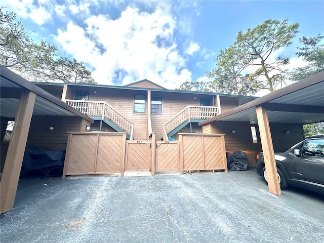 view of property exterior featuring a carport, stairway, and fence