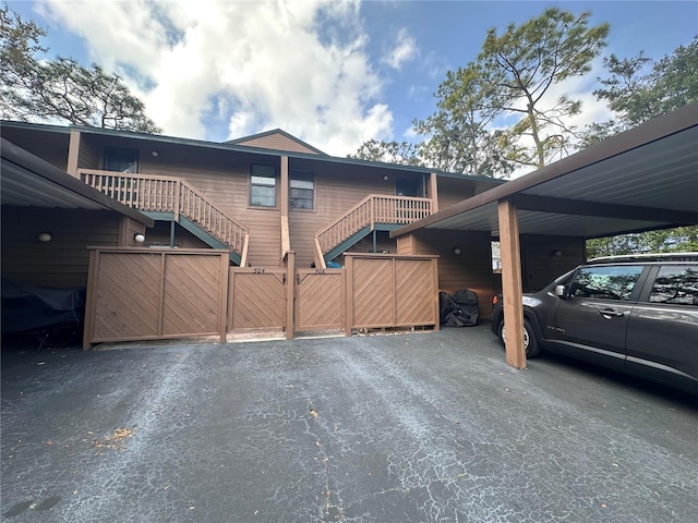 exterior space featuring an attached carport, stairway, a gate, and fence