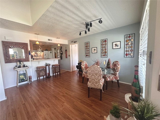 dining area with wood finished floors, visible vents, baseboards, track lighting, and a textured ceiling