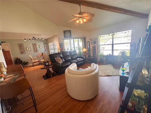 living room featuring a ceiling fan, vaulted ceiling with beams, wood finished floors, and a textured ceiling