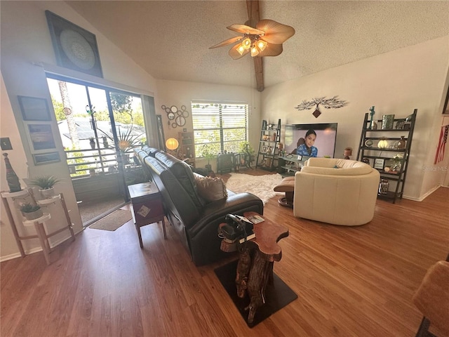 living room with a ceiling fan, lofted ceiling, wood finished floors, and a textured ceiling