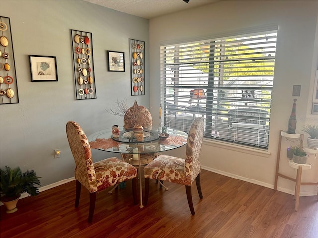 dining space with baseboards and wood finished floors