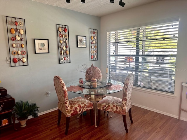 dining area with baseboards, a textured ceiling, and wood finished floors