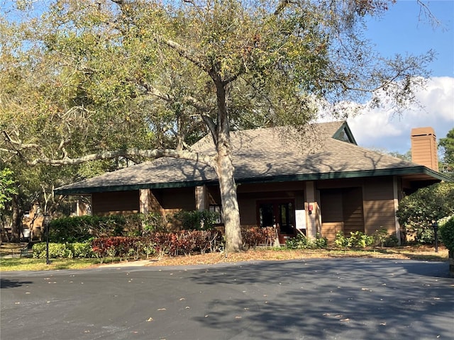 view of front of property with a shingled roof and a chimney