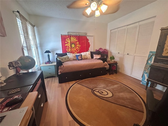 bedroom featuring a closet, a textured ceiling, ceiling fan, and light wood finished floors