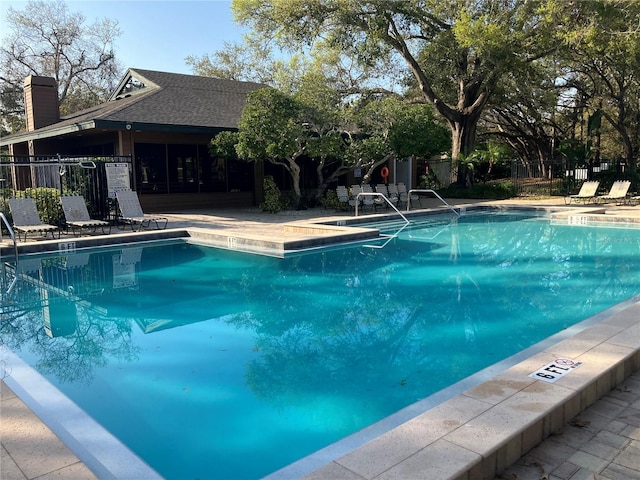 pool with a patio area and fence