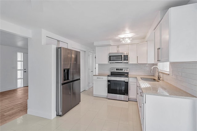 kitchen with sink, white cabinetry, appliances with stainless steel finishes, and a wealth of natural light