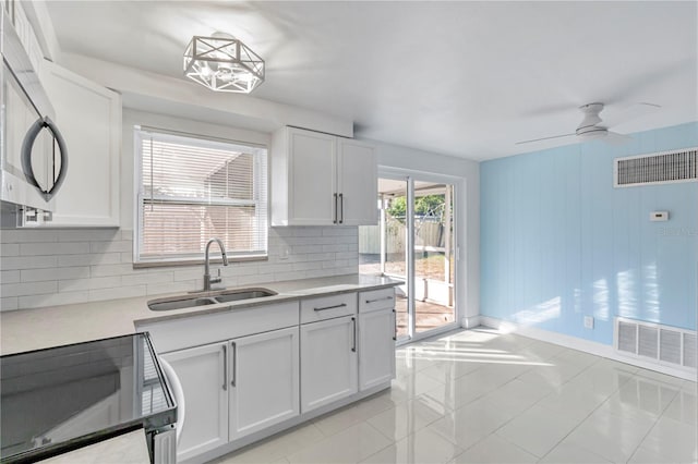 kitchen with light tile patterned floors, sink, white cabinets, and stove