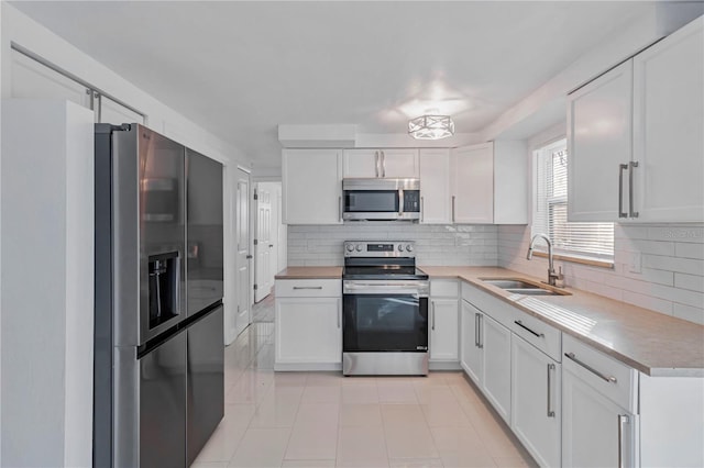 kitchen featuring light tile patterned floors, white cabinetry, stainless steel appliances, backsplash, and sink