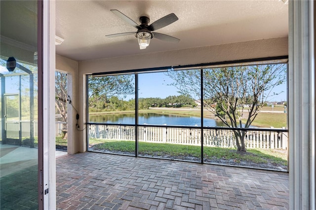 unfurnished sunroom featuring ceiling fan and a water view