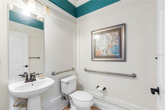 bathroom with toilet, crown molding, and sink