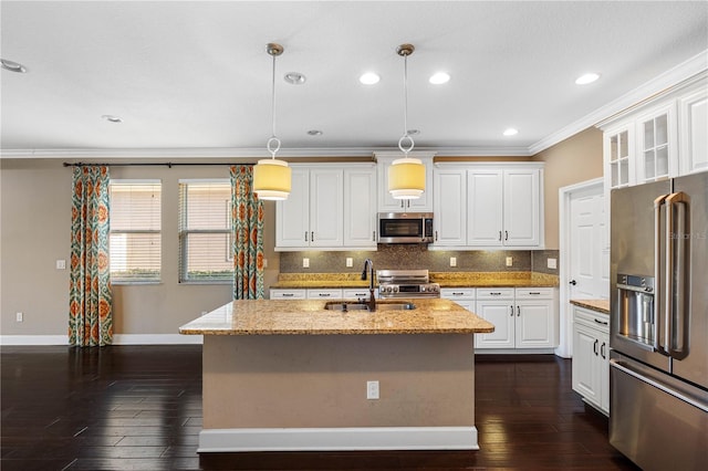 kitchen with appliances with stainless steel finishes, light stone counters, a kitchen island with sink, decorative light fixtures, and white cabinets