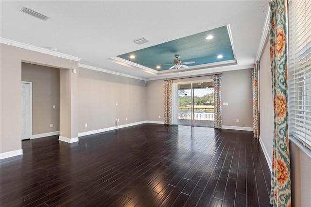 empty room featuring a raised ceiling, ceiling fan, dark wood-type flooring, and crown molding