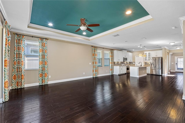 unfurnished living room with a raised ceiling, crown molding, sink, and dark wood-type flooring