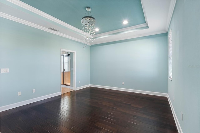 unfurnished room with a raised ceiling, crown molding, a chandelier, and dark hardwood / wood-style floors