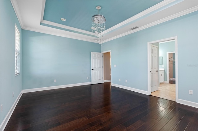 spare room featuring hardwood / wood-style floors, a tray ceiling, crown molding, and a notable chandelier