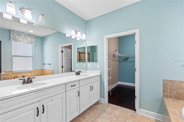 bathroom featuring tile patterned flooring, vanity, and tiled bath