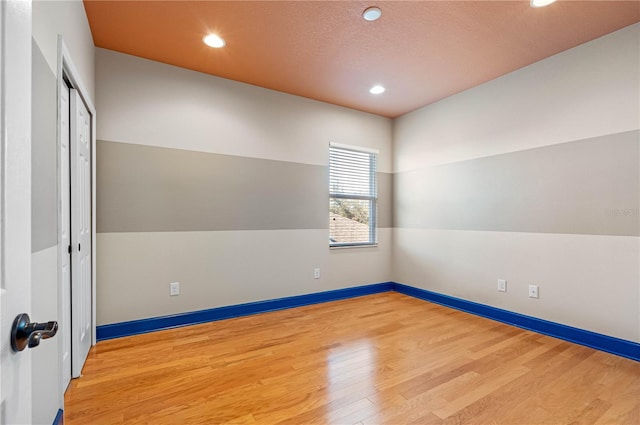 empty room featuring hardwood / wood-style floors, a textured ceiling, and vaulted ceiling