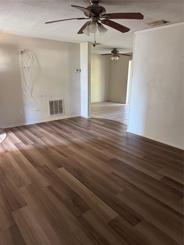 empty room with a textured ceiling, ceiling fan, and dark wood-type flooring