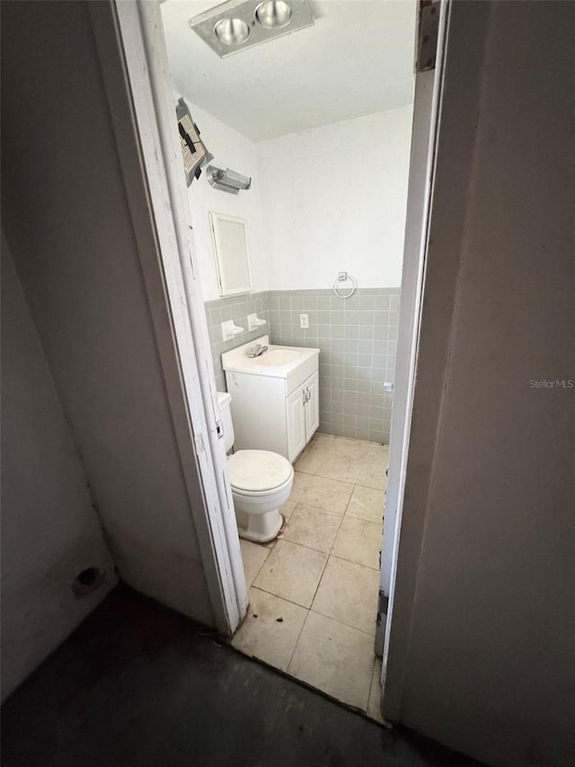 bathroom featuring tile patterned flooring, vanity, tile walls, and toilet