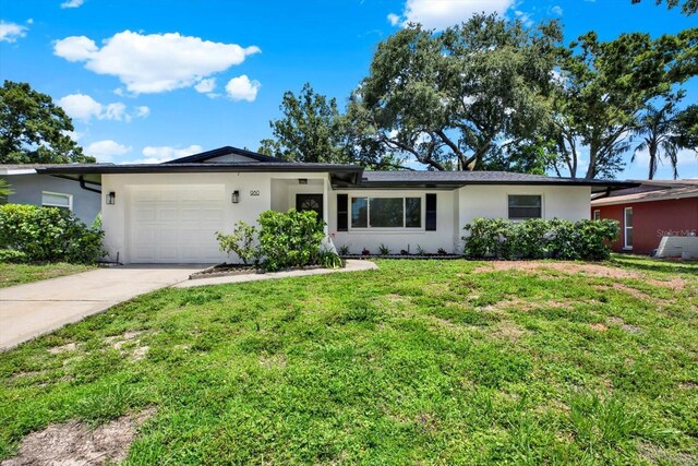 980 5th Ave NE, Largo, FL 33770 - ranch-style house with stucco siding, driveway, an attached garage, and a front lawn