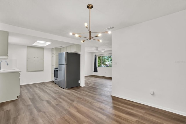 980 5th Ave NE, Largo, FL 33770 - kitchen with appliances with stainless steel finishes, wood finished floors, light countertops, and a chandelier