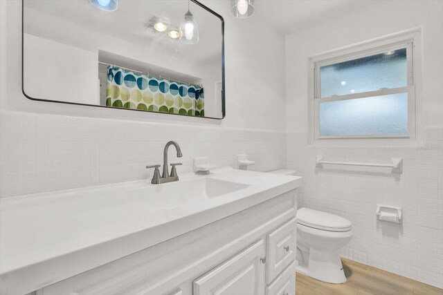 980 5th Ave NE, Largo, FL 33770 - full bathroom featuring tile walls, vanity, wood finished floors, a wainscoted wall, and curtained shower