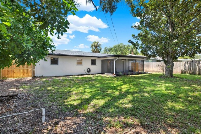 980 5th Ave NE, Largo, FL 33770 - back of house featuring a fenced backyard, a sunroom, and stucco siding