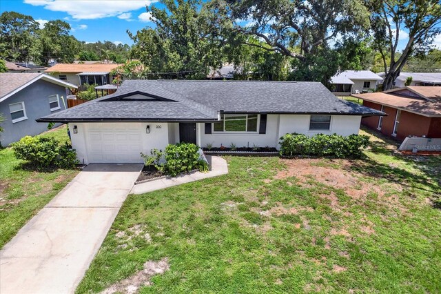 980 5th Ave NE, Largo, FL 33770 - single story home with a shingled roof, an attached garage, a front lawn, driveway, and stucco siding