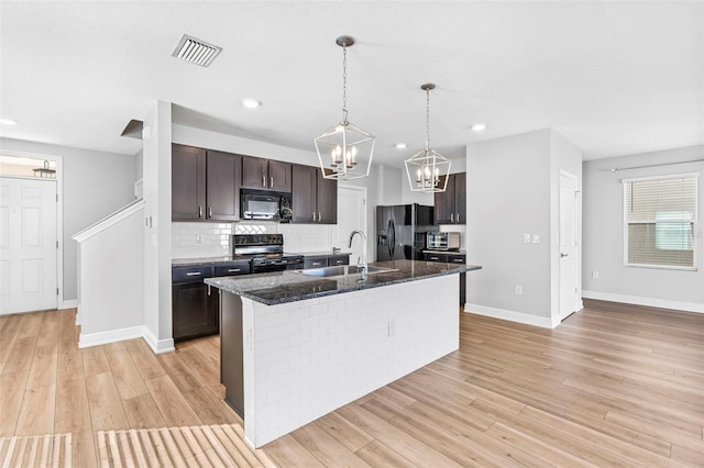 kitchen with sink, light hardwood / wood-style flooring, a kitchen island with sink, and black appliances