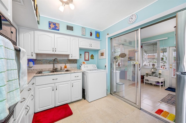 laundry area featuring light tile patterned flooring, washer / dryer, and sink