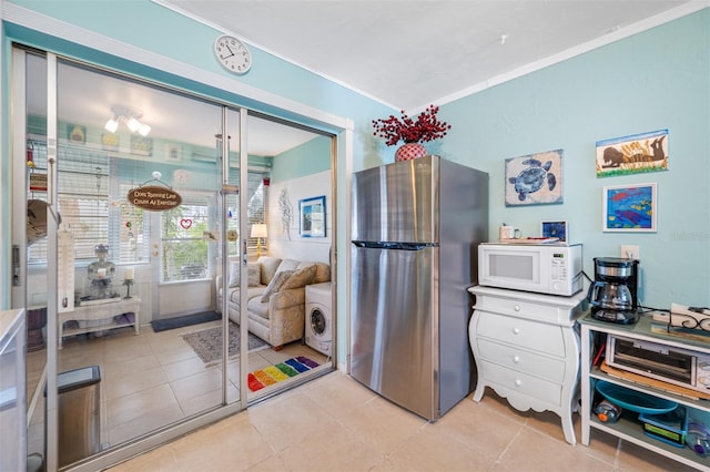 kitchen featuring stainless steel fridge, light tile patterned floors, and crown molding