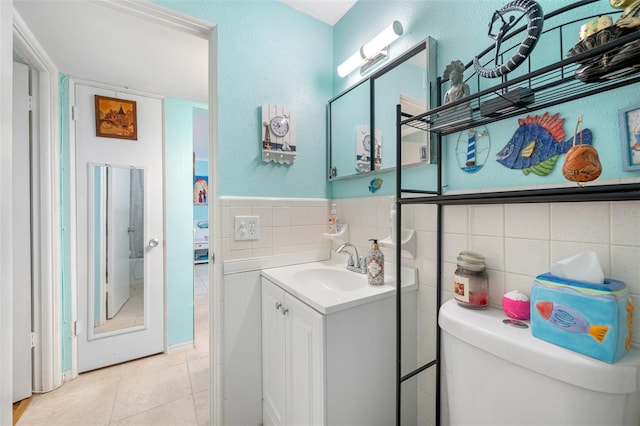 bathroom featuring tile patterned flooring, vanity, tile walls, and toilet