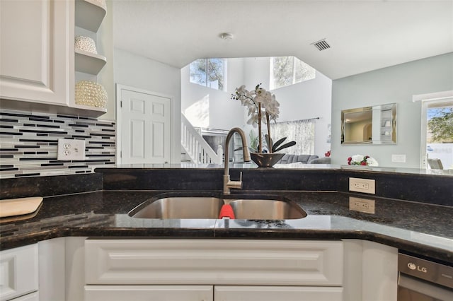 kitchen featuring backsplash, white cabinetry, dark stone countertops, and sink