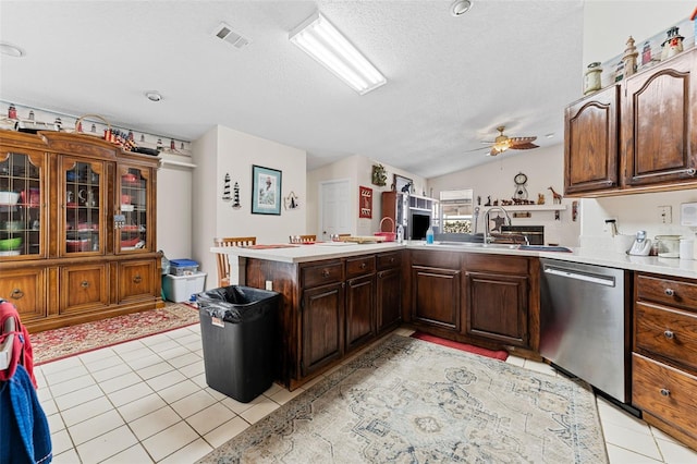 kitchen featuring ceiling fan, dishwasher, kitchen peninsula, lofted ceiling, and light tile patterned flooring