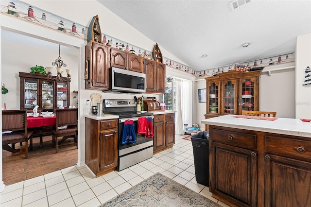 kitchen with appliances with stainless steel finishes, light wood-type flooring, a textured ceiling, an inviting chandelier, and lofted ceiling