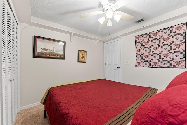 bedroom with ceiling fan, carpet floors, and a textured ceiling