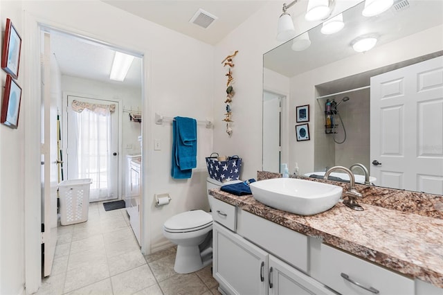 bathroom with tile patterned flooring, a tile shower, vanity, and toilet