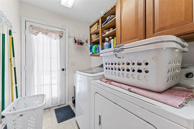 laundry room with washer and dryer, a healthy amount of sunlight, cabinets, and a textured ceiling