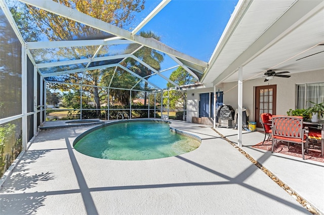 view of pool with glass enclosure, ceiling fan, and a patio area