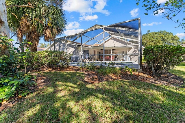 rear view of property featuring a lanai and a lawn