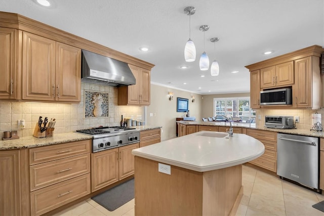 kitchen with wall chimney range hood, sink, hanging light fixtures, stainless steel appliances, and an island with sink