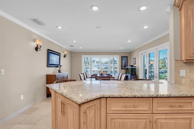 kitchen with crown molding, light brown cabinetry, light stone counters, and kitchen peninsula